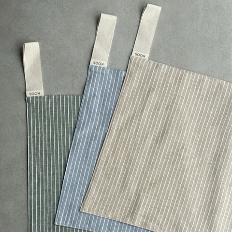 4. Flat lay of three linen sauna seat covers in different colors with light stripes and cotton hooks, showing design variety.