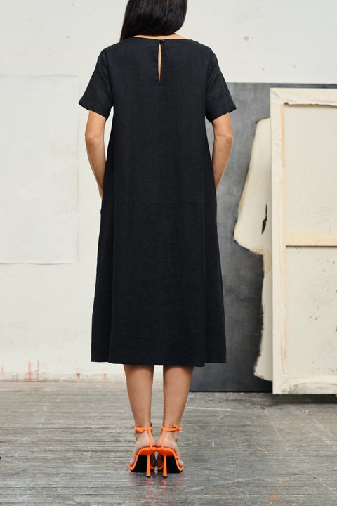 2. Back view of black linen dress with button closure, worn by woman with orange heels
