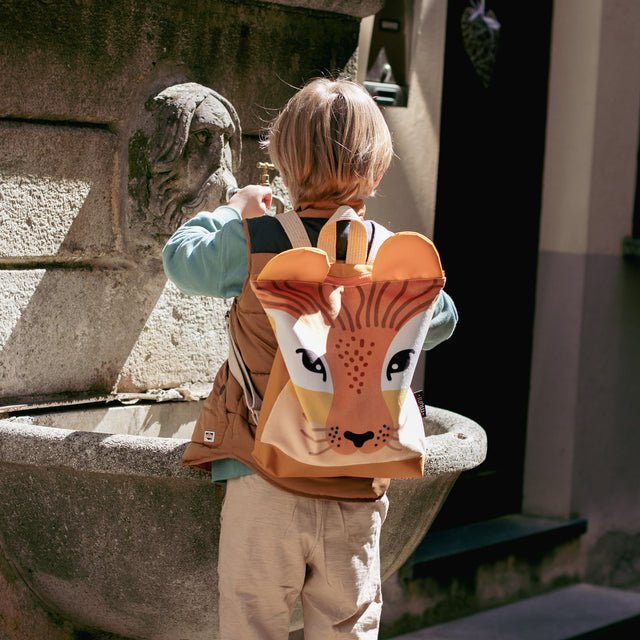 4. Boy with Muni lion backpack standing by a fountain