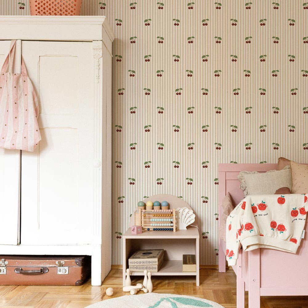 1. Children's room with little cherries on beige stripes wallpaper, white wardrobe, pink bed, and toys creating a playful vintage atmosphere