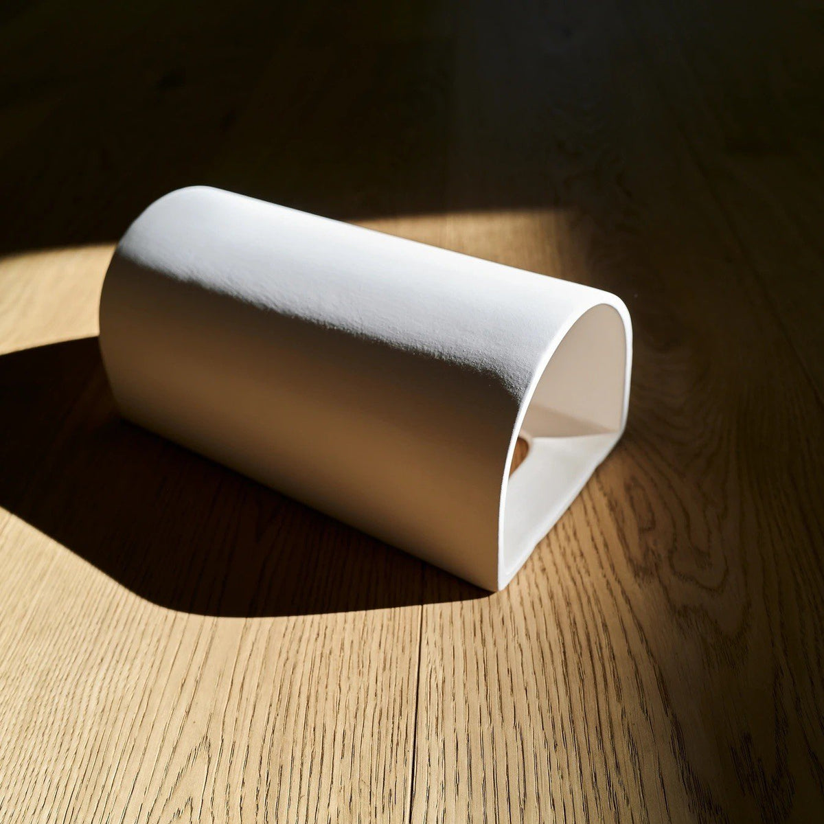 2. Studio shot of ceramic wall light in extra matte white on wooden floor