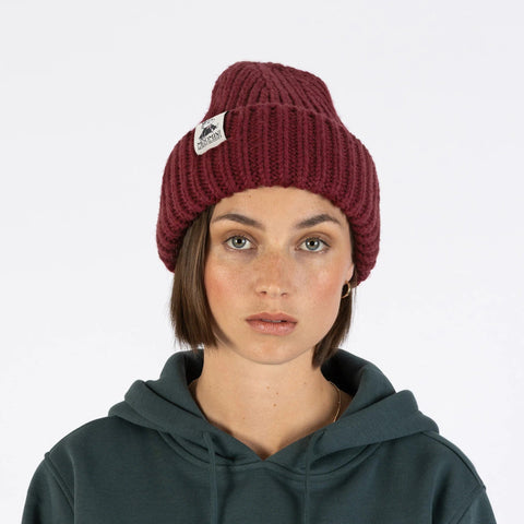 1. Woman wearing burgundy chunky beanie by Moomin NordicBuddies, front view, with green hoodie, studio background