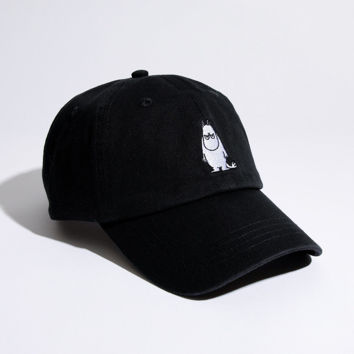 3. Studio shot of black Grumpy Moomintroll Dad Cap with front embroidery, angled view