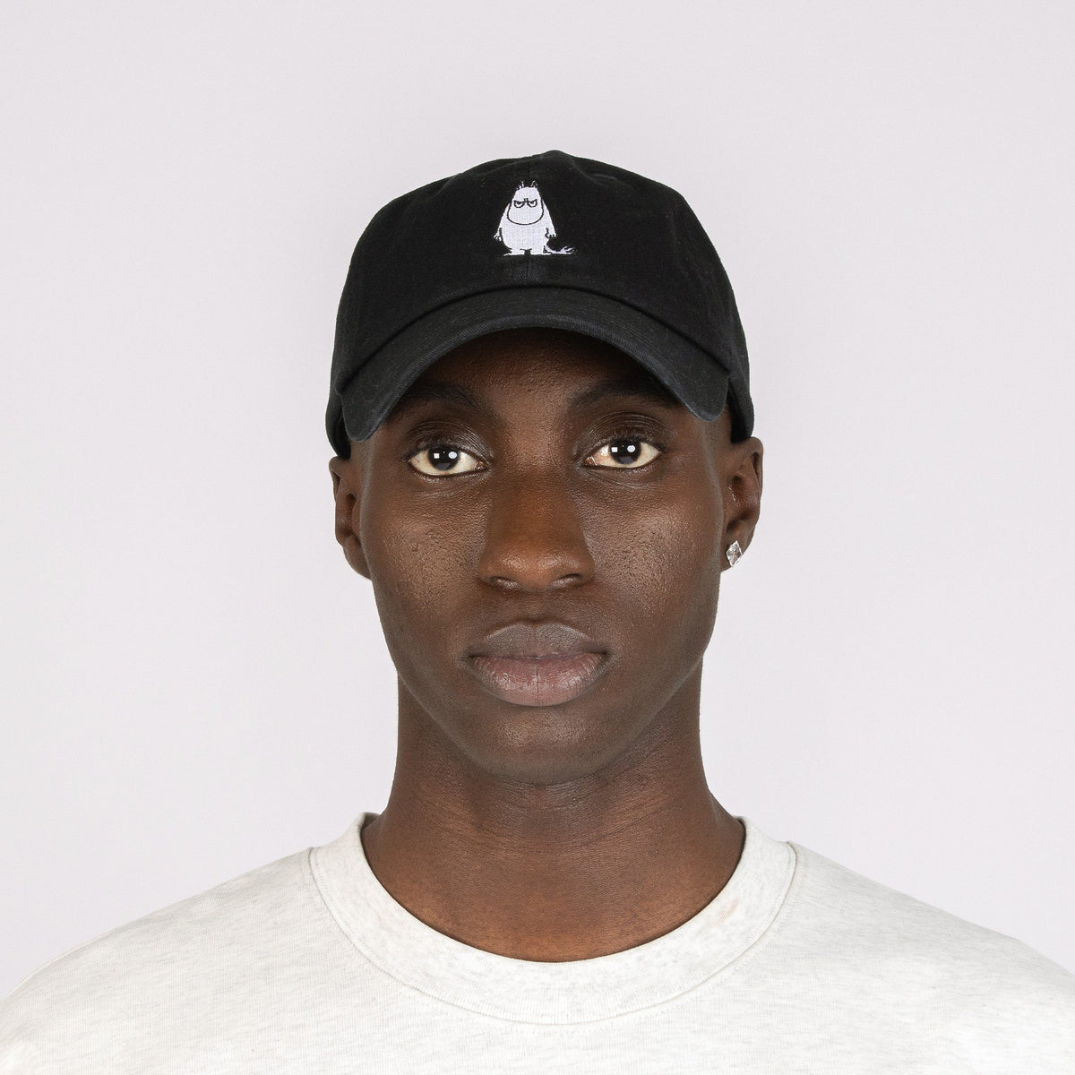 1. Black Grumpy Moomintroll Dad Cap worn by male model, front view showcasing embroidered design