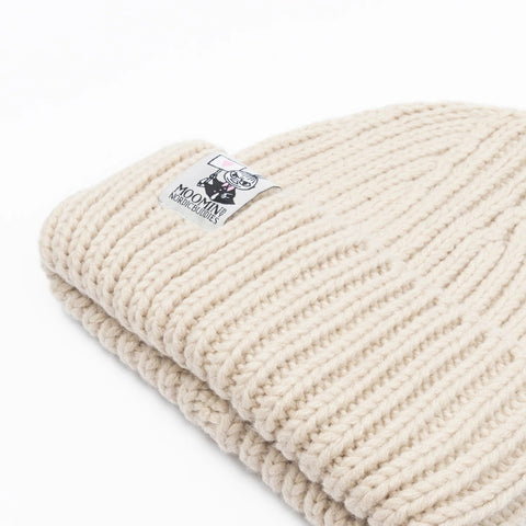 3. Close-up of folded beige chunky beanie showing Moomin NordicBuddies logo on ribbed texture