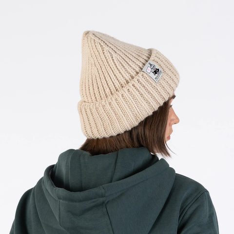 1. Woman wearing beige chunky beanie by Moomin NordicBuddies shown from side with green hoodie in studio setting
