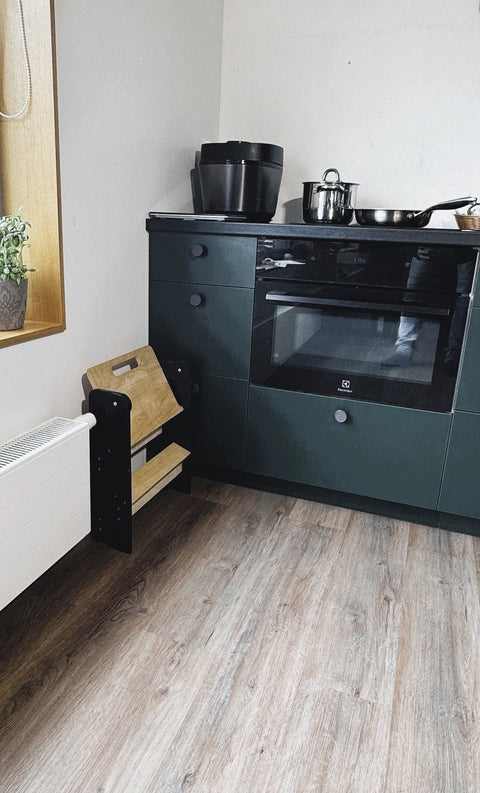1. Wooden step stool folded and placed beside a kitchen cabinet