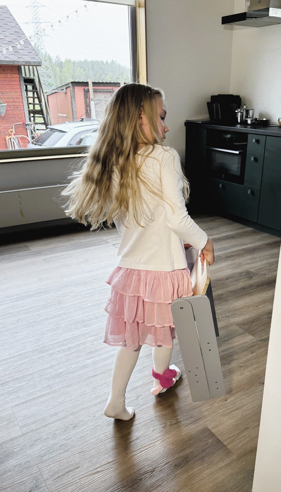 1. Girl walking with folded wooden step stool in a kitchen