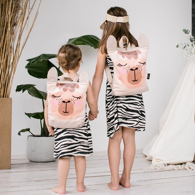 3. Sisters with Muni llama backpacks, showing front design and adjustable straps in lifestyle setting