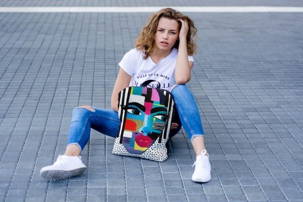 7. Woman sitting on pavement with Garbanota BACKPACK LOLITA, displaying unique artistic pattern