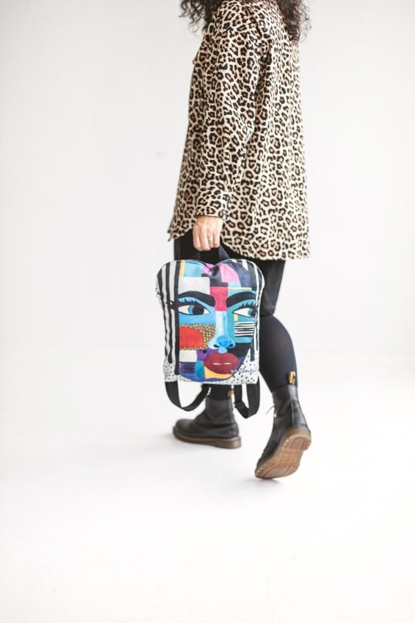 4. Studio shot of woman holding Garbanota BACKPACK LOLITA, showcasing artistic design and leopard print coat