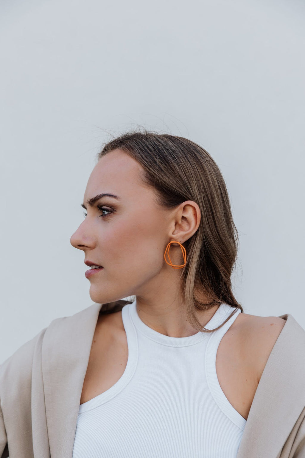 1. Woman wearing Lisa Kroeber Jewellery Loops Earrings in orange, showcasing organic shape and lightweight design