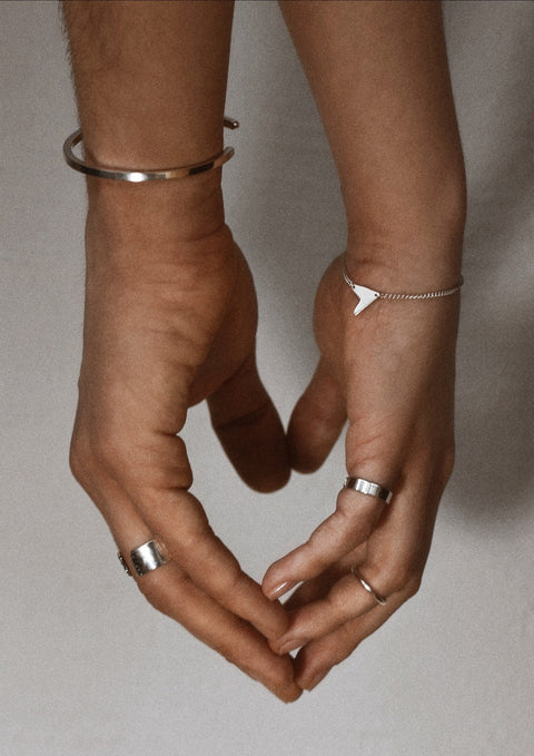 3. Women's Love Bracelet in silver styled with other silver jewelry, shown on hand in monochrome setting