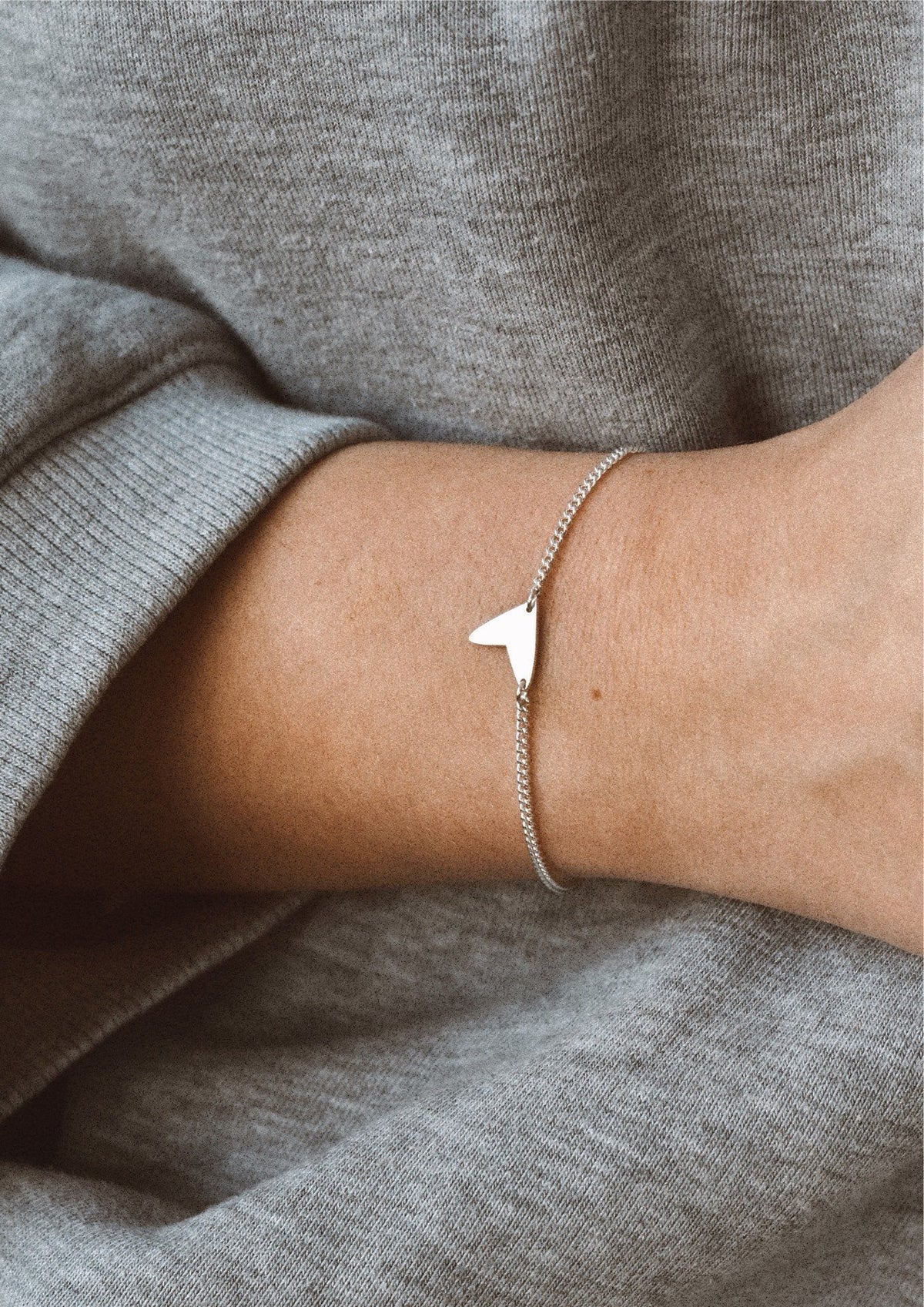 1. Women's Love Bracelet in sterling silver worn on wrist with grey sweater, showcasing delicate design