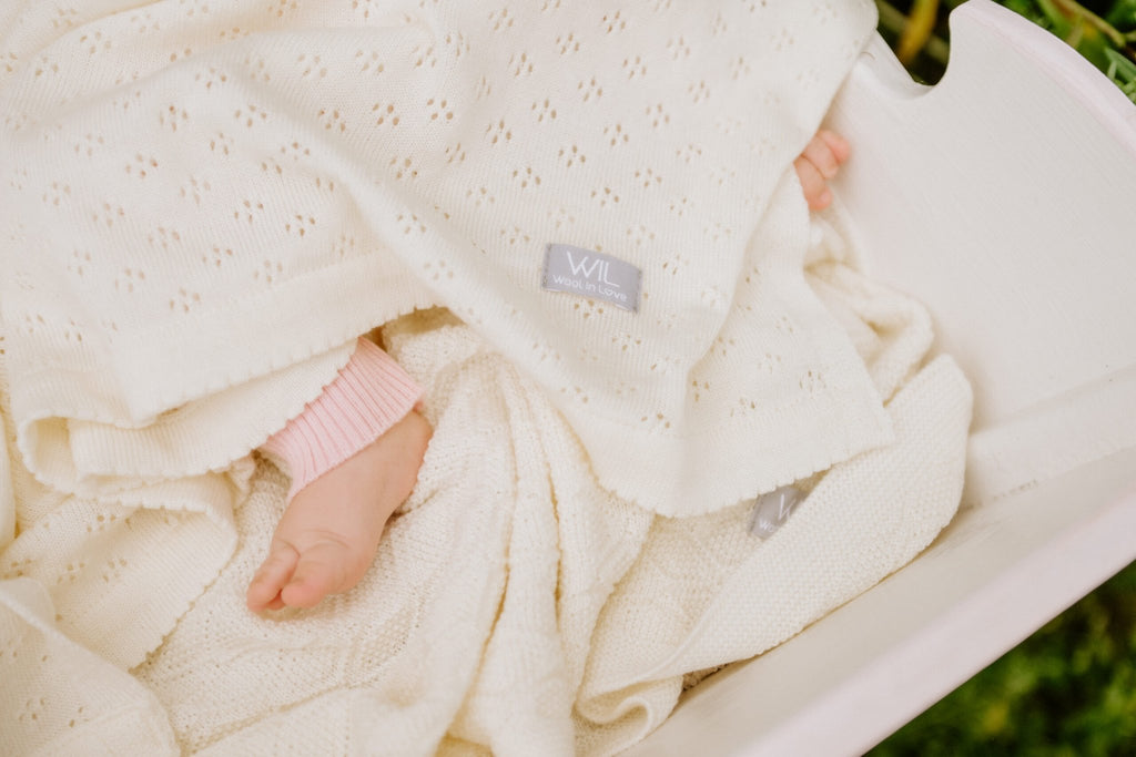 7. Close-up of baby's foot under a white merino wool blanket with visible Wool In Love label