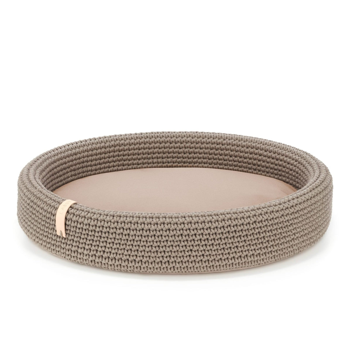 2. Light brown oval dog bed by Labbvenn made of braided cotton and polyester with removable cushion, shown in studio setting highlighting texture and design