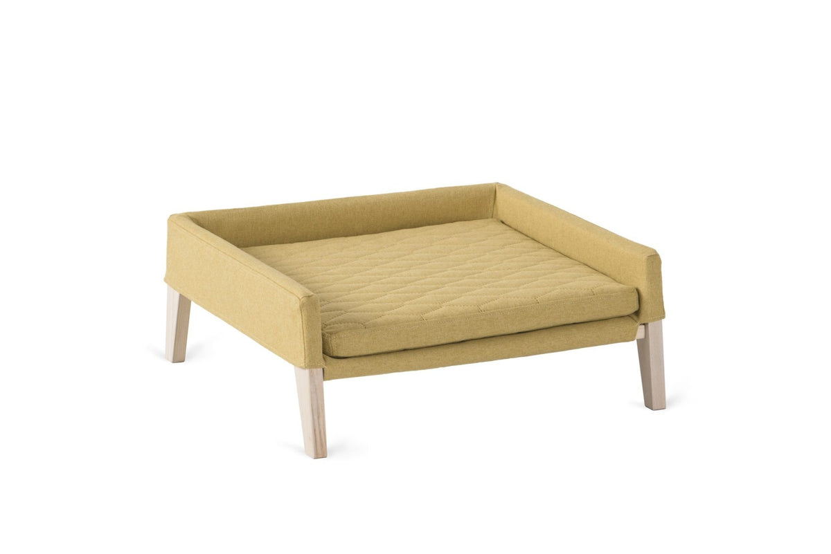 2. Honey-colored pet bed for cats and small dogs with quilted cushion and ash wood frame, shown in studio setting highlighting minimalist design and comfort features