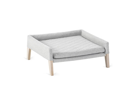 2. Light grey dog and cat bed with quilted pillow and ash wood legs, designed for small pets, shown in studio setting highlighting minimalist design and comfort features