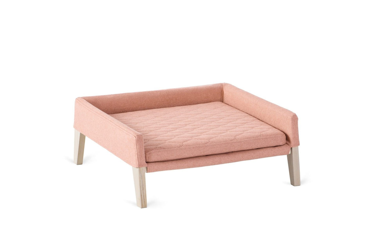 2. Labbvenn Lulu dog and cat bed in raspberry color with quilted pillow and ash wood legs, shown in studio setting highlighting minimalist design and comfort features