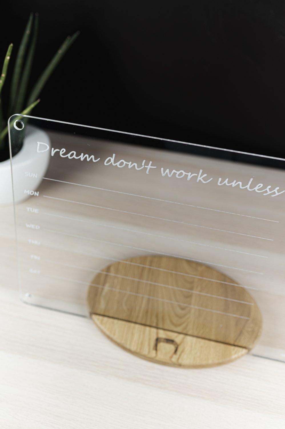 2. Top view of clear acrylic school planner with quote 'Dream don't work unless' on wooden stand, showing weekly layout