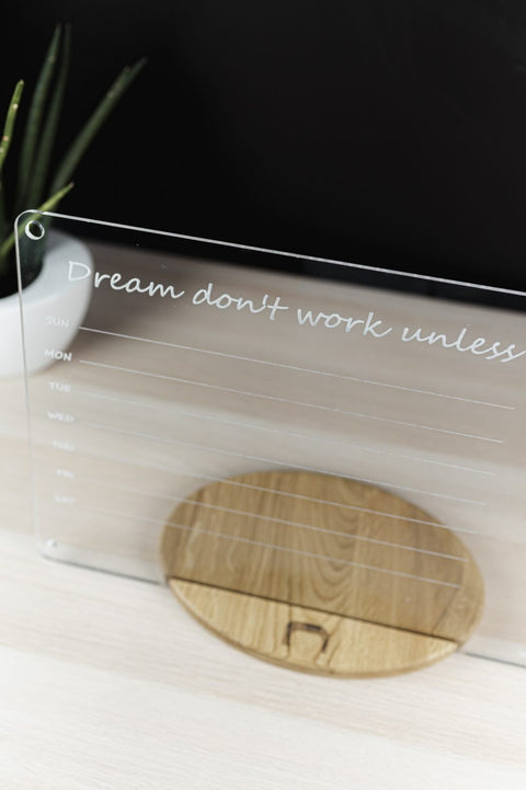2. Top view of clear acrylic school planner with quote 'Dream don't work unless' on wooden stand, showing weekly layout