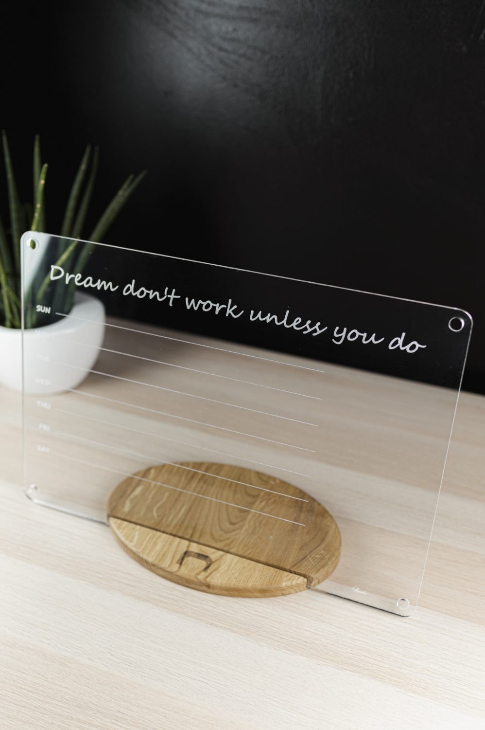 5. Angled view of acrylic school planner with motivational quote and weekly schedule, on wooden stand