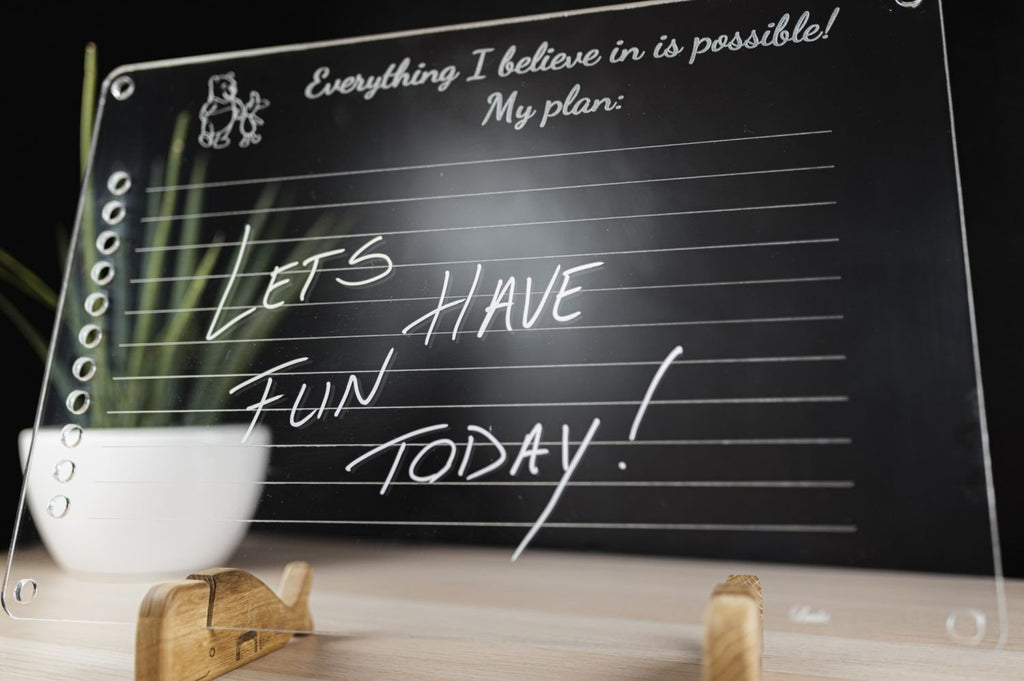2. Close-up of Luula acrylic planner with handwritten message 'Let's have fun today!' on wooden stand