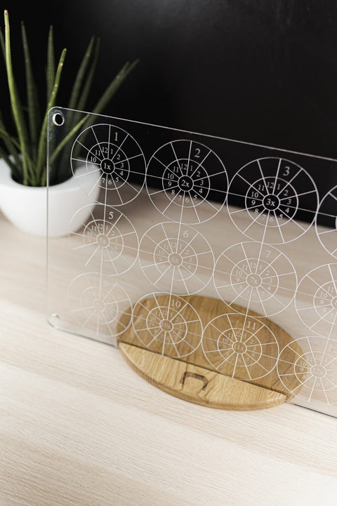 5. LUULA multiplication board on wooden stand with plant, featuring laser-engraved tables on clear acrylic