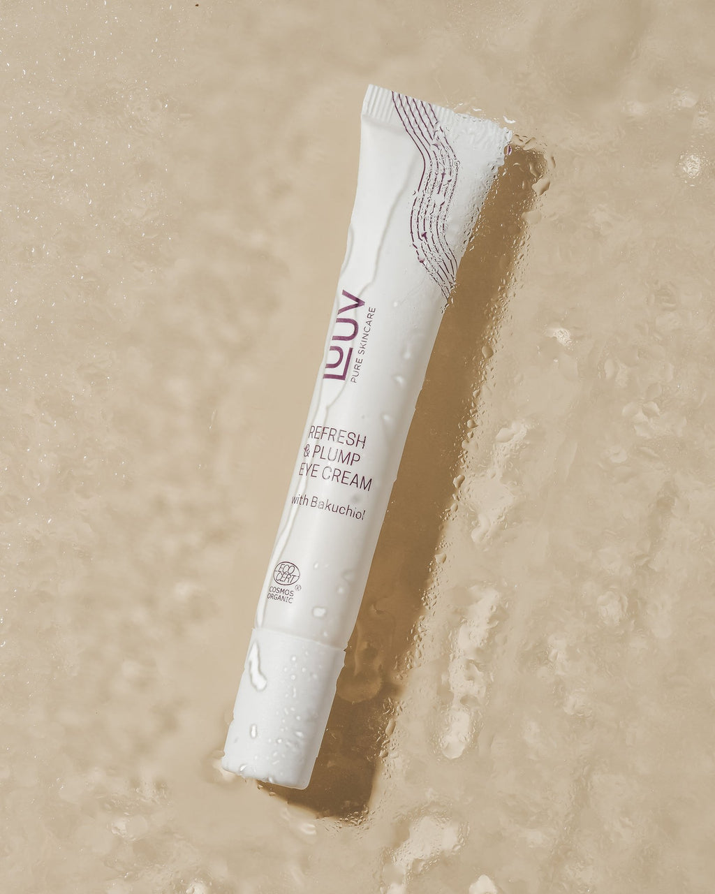 1. LUUV Refresh & Plump Eye Cream tube with Bakuchiol on a wet surface, highlighting COSMOS ECOCERT Organic certification