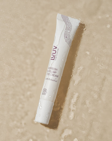 1. LUUV Refresh & Plump Eye Cream tube with Bakuchiol on a wet surface, highlighting COSMOS ECOCERT Organic certification
