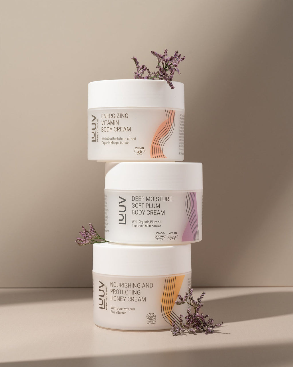 4. LUUV body cream stack with Deep Moisture Soft Plum, Energizing Vitamin, and Nourishing Honey, adorned with purple flowers