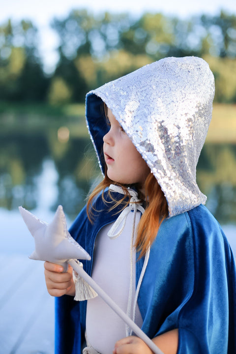 4. Close-up of child in blue cape with silver hood holding a star wand by a lake