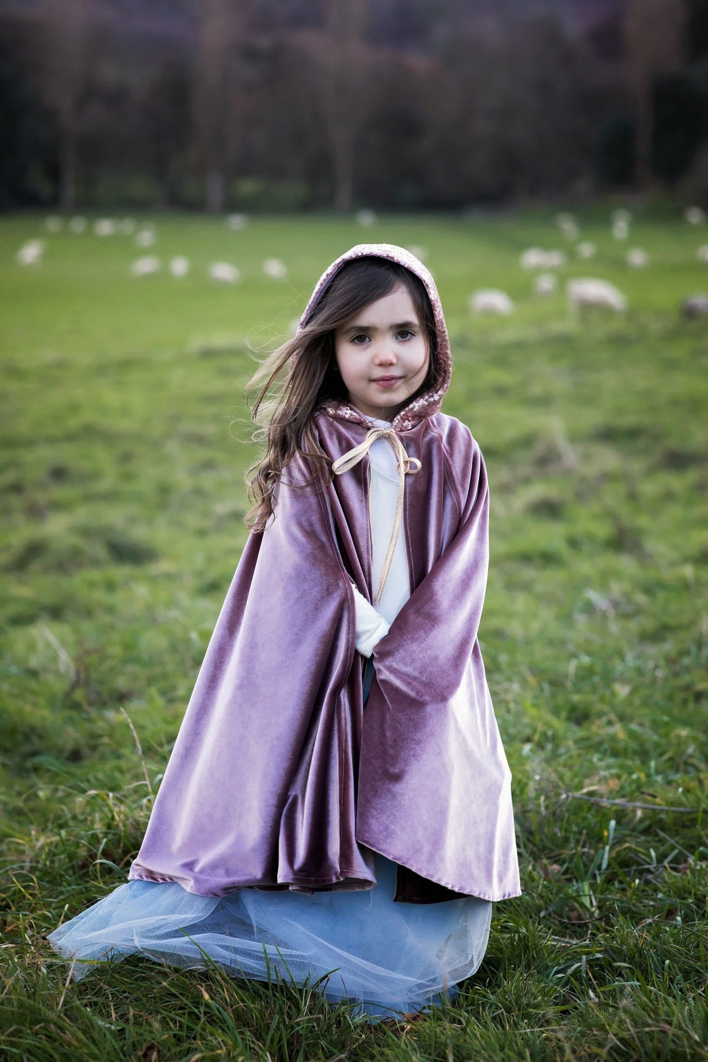 1. Young girl in cosmic pearl cape with hood, standing in a field, highlighting the cape's velour texture and fairy tale style