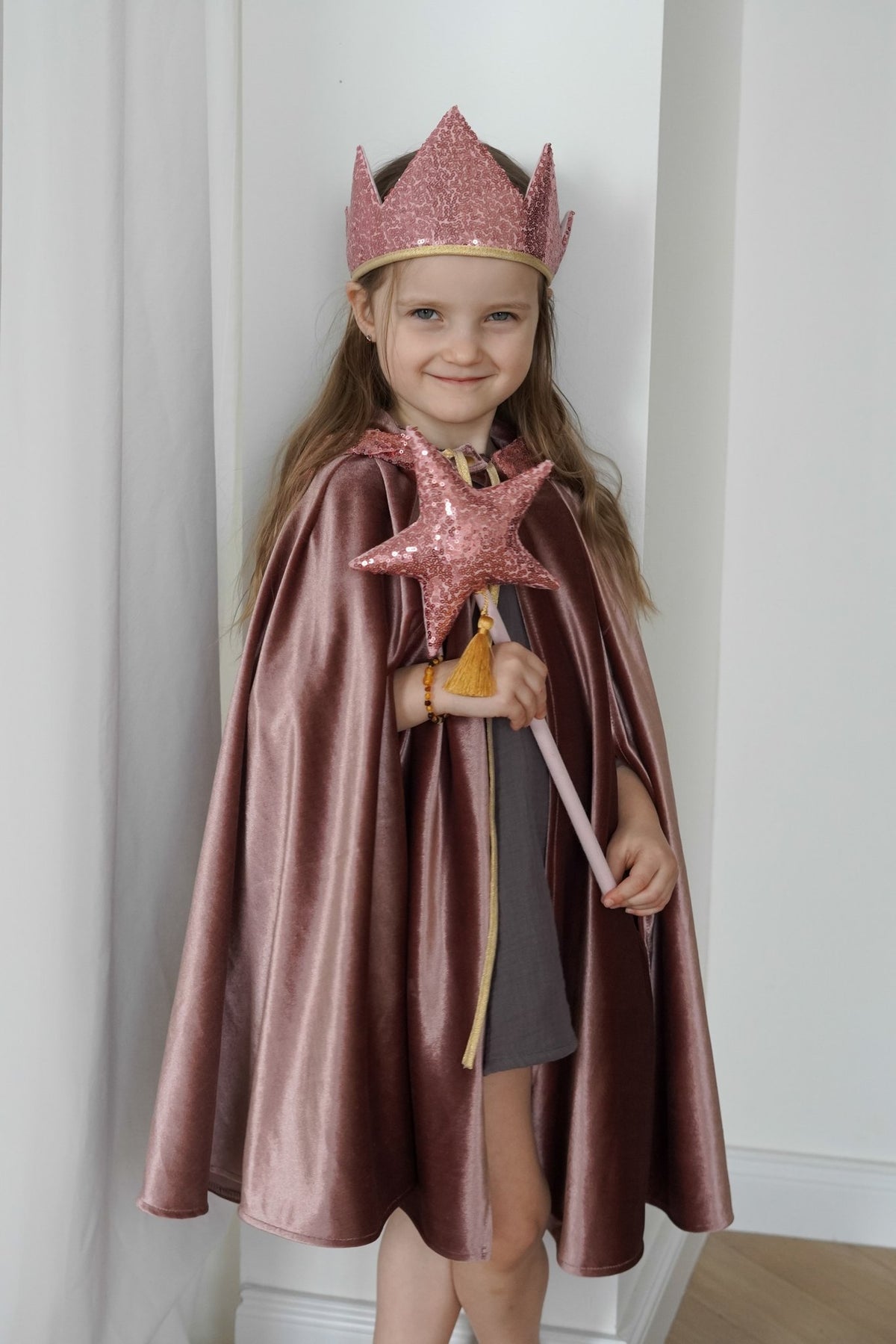 1. Child dressed in cosmic pearl cape with pink crown and star wand, showcasing the velour fabric and magical theme