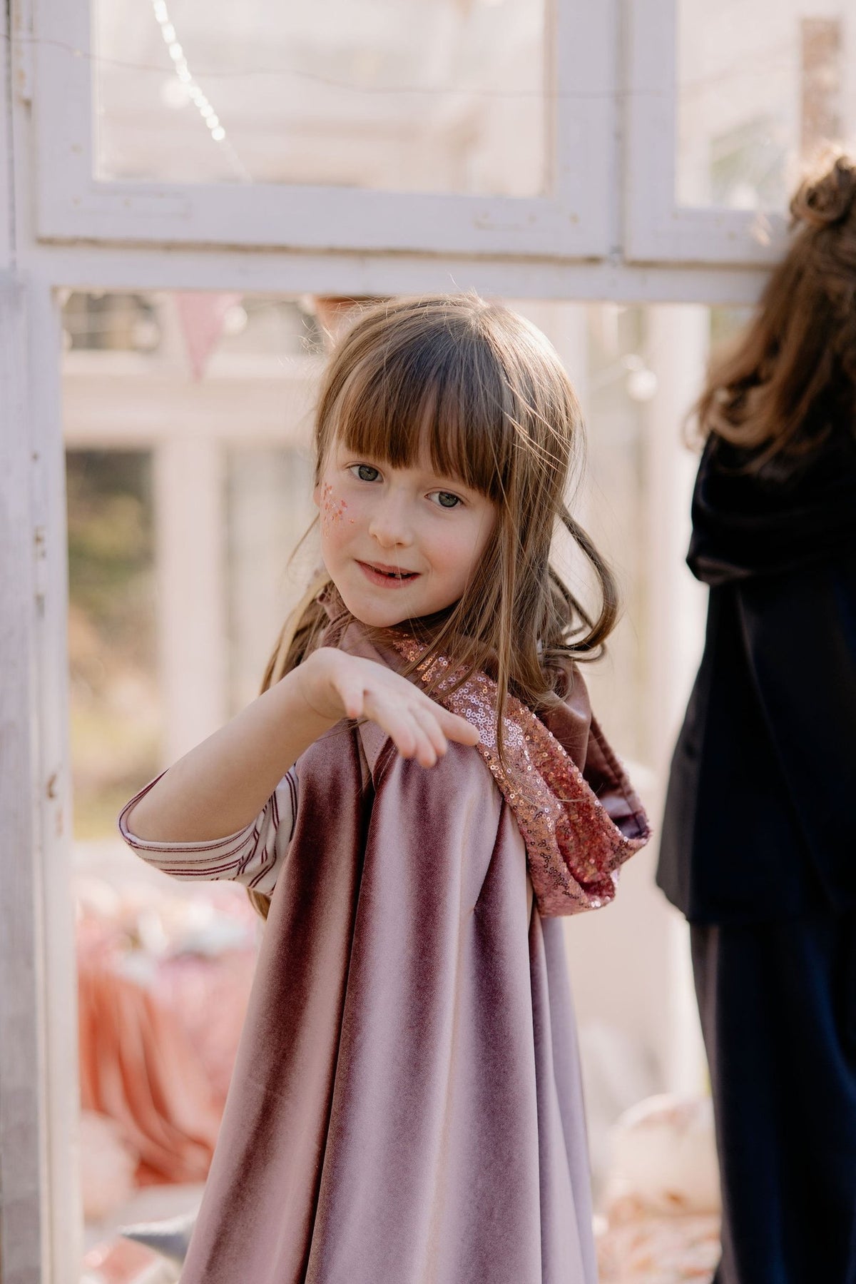 1. Child wearing cosmic pearl cape with hood indoors, showing playful and magical design by moi mili