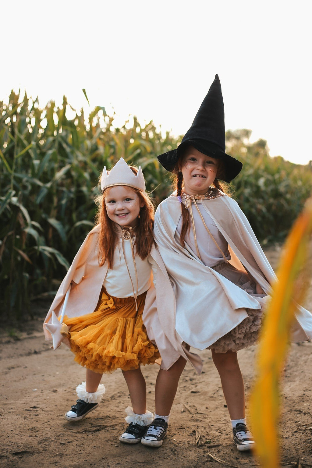 5. Two girls in cream capes and hats posing in cornfield