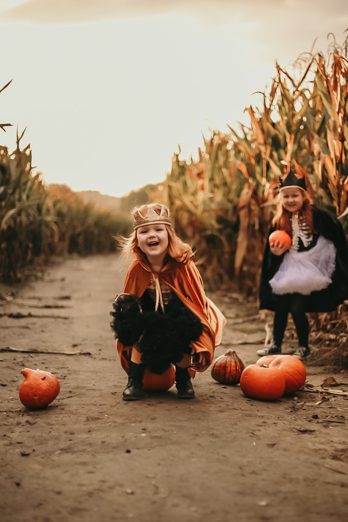 4. Children in golden and black capes with pumpkins on dirt path