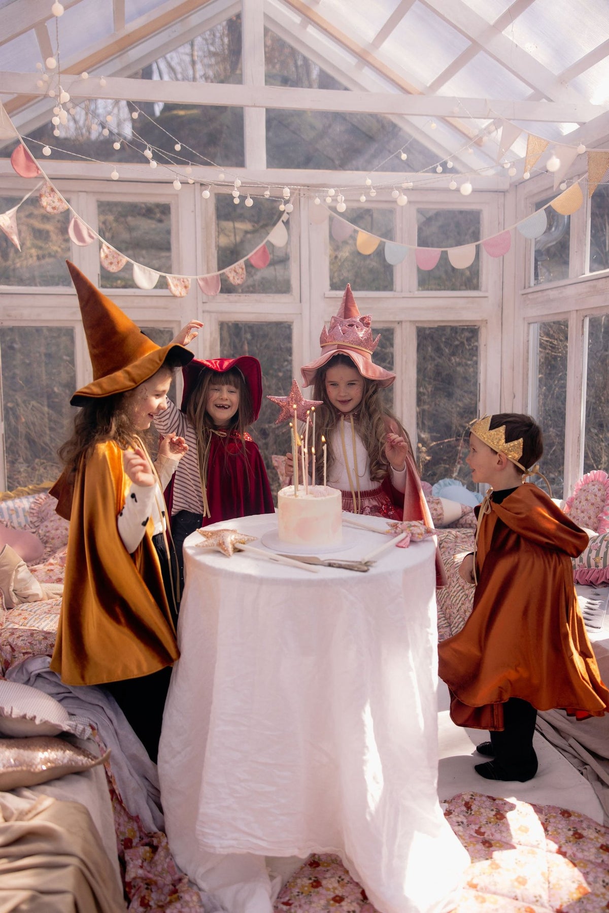 11. Children in colorful capes around table in sunlit room