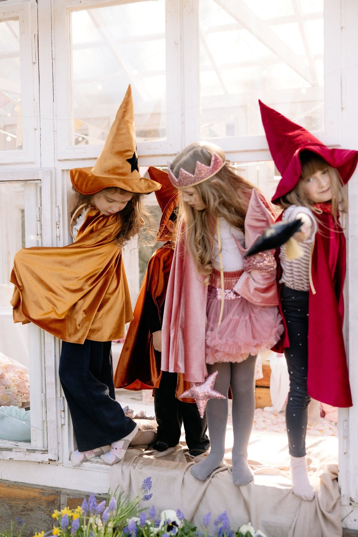 7. Children in golden, pink, and red capes playing by window