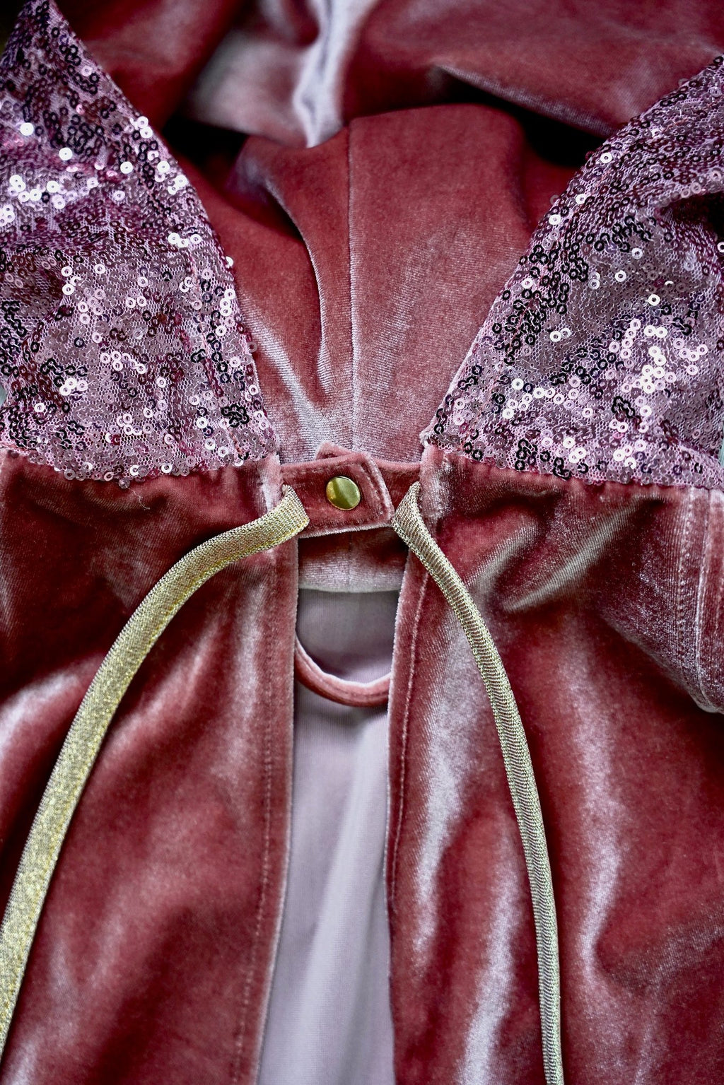 11. Close-up of pink velour cape showing snap button and lace detail