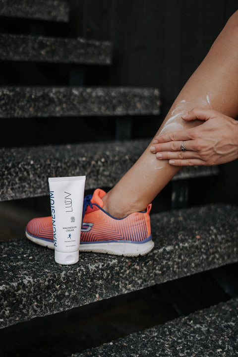 5. Person applying LUUV Magnesium Cream to leg on outdoor steps with colorful sneakers