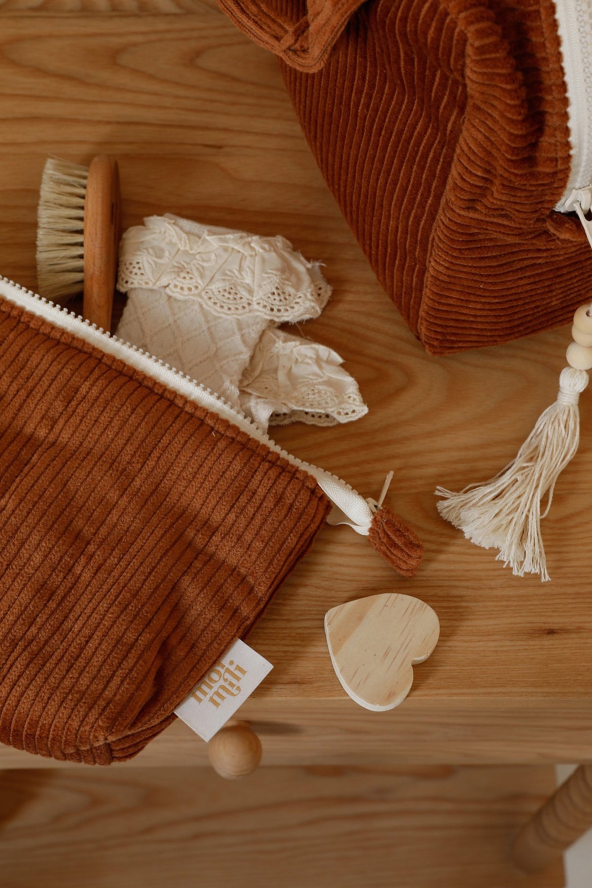 10. Close-up of small caramel makeup bag with zipper, placed on wooden surface with lace and brush