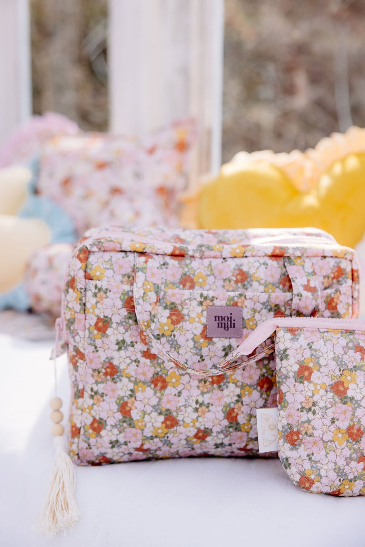 1. Floral print makeup bag set with pink and orange flowers, displayed outdoors with colorful pillows