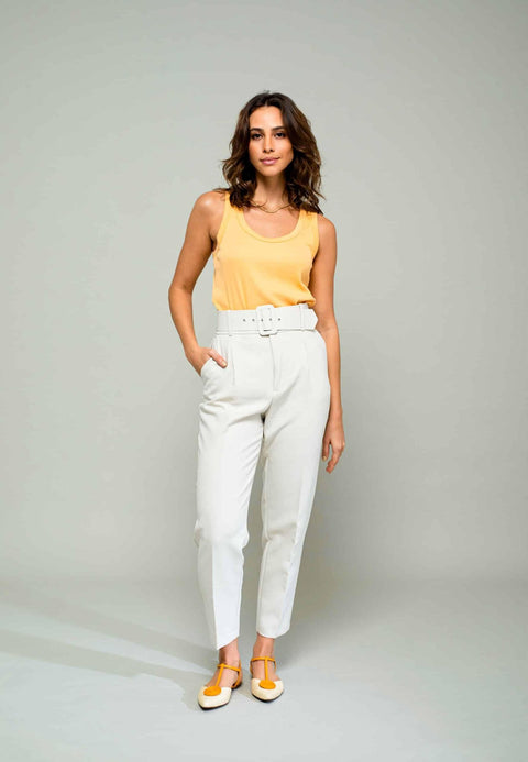 1. Women's Mangará Acerola sandals in natural color worn by model with yellow top and white pants