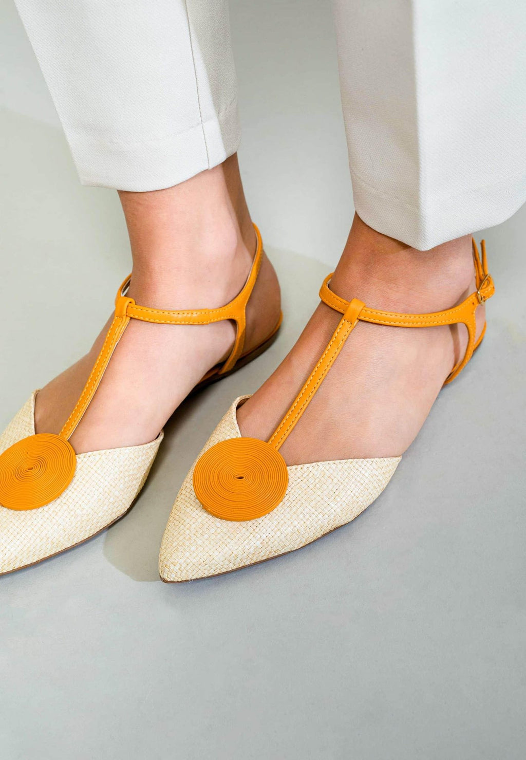 3. Close-up of women's Mangará Acerola sandals in natural color with yellow accents, worn with white pants