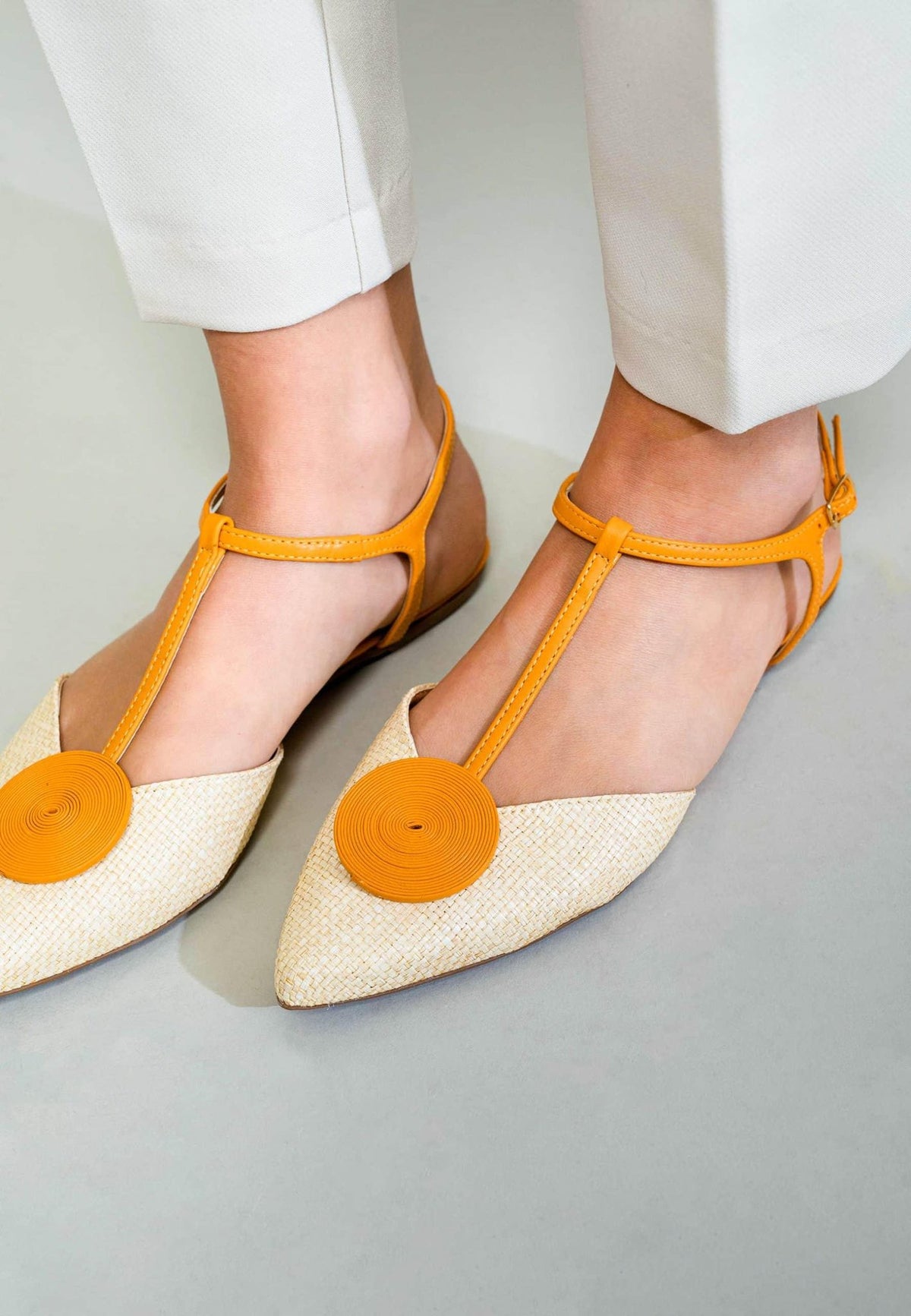 3. Close-up of women's Mangará Acerola sandals in natural color with yellow accents, worn with white pants