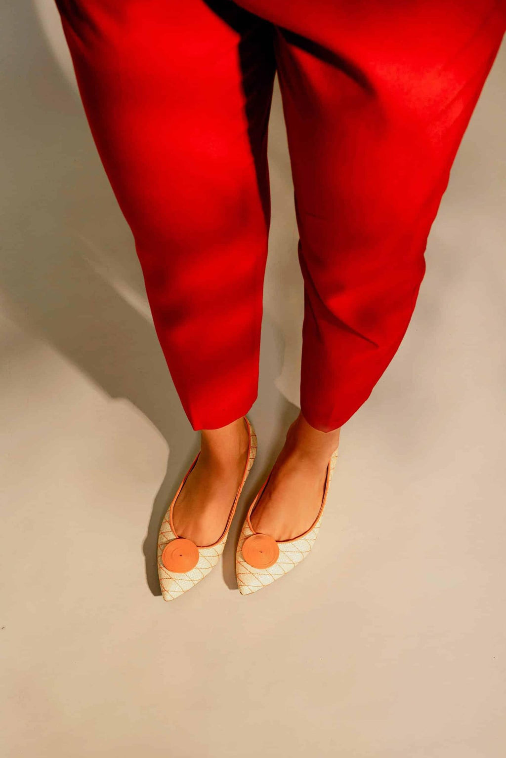 1. Woman wearing Mangará Coroba Ballerinas with red pants, showcasing summer elegance and raffia fabric