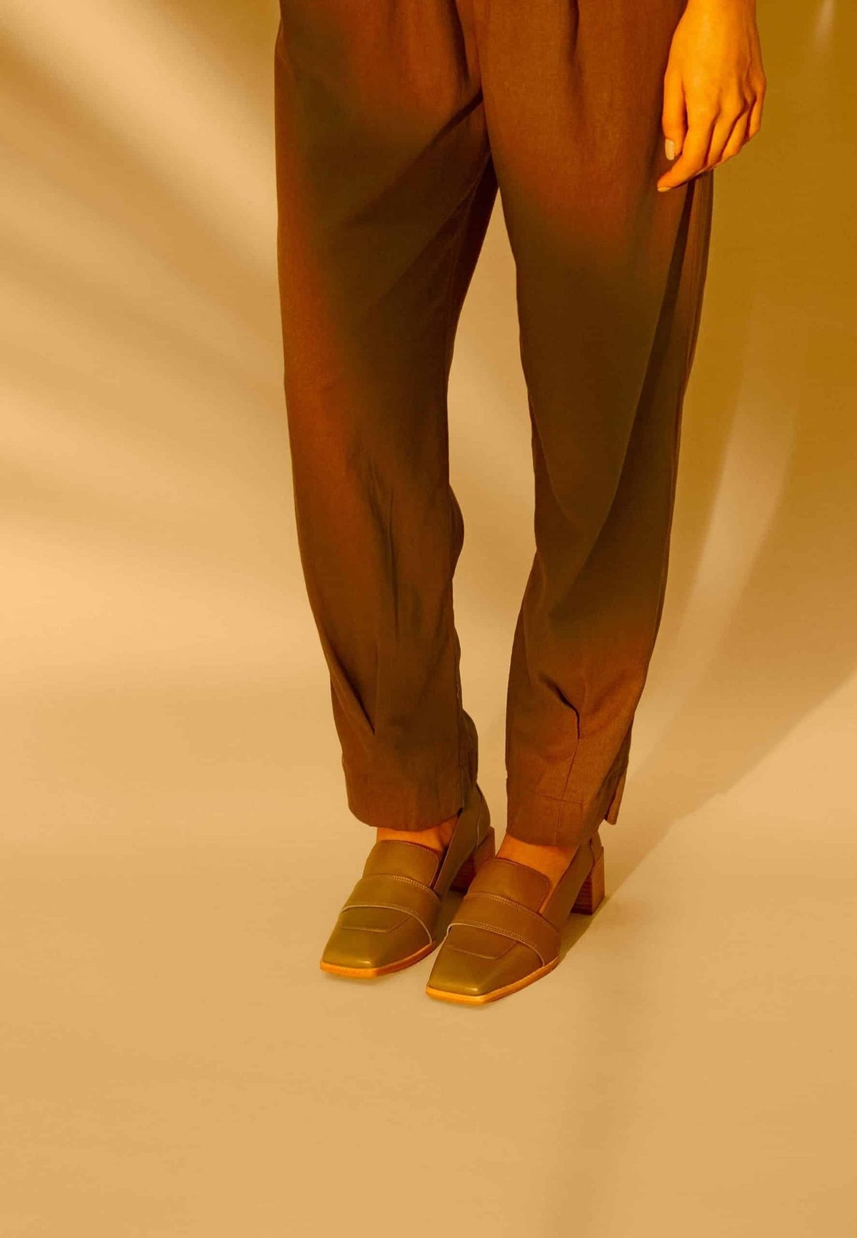 2. Close-up of women's Mangará Louro Leather Loafers in beige worn with trousers in studio