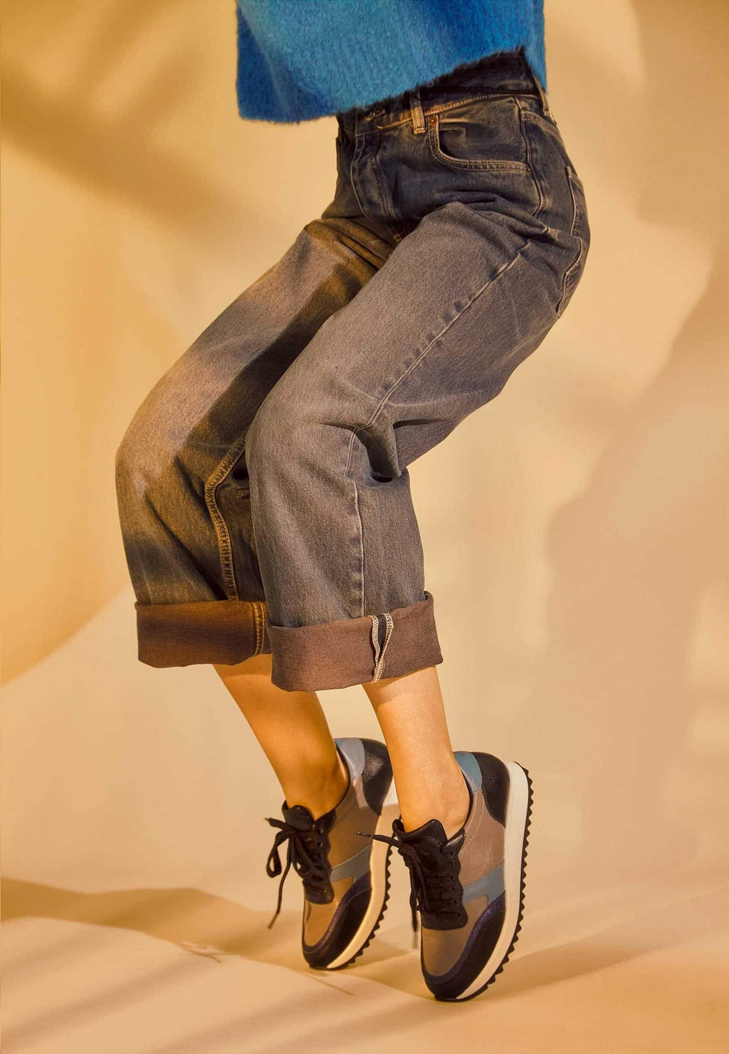 1. Women's Mangará Buriri sneakers in grey, blue, and black worn by a model in a casual setting