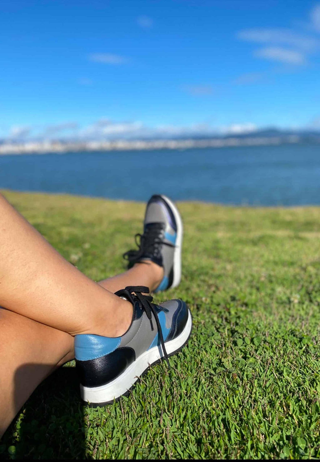 3. Women's Mangará Buriri sneakers in grey, blue, and black worn outdoors by a lake